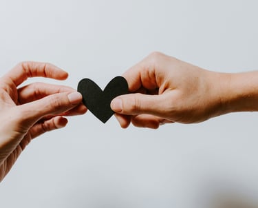 two hands holding a paper heart shaped paper cutout