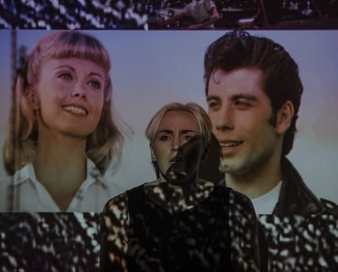Mary performs during the Adelaide Fringe. She stands in front of a projection of Greese characters