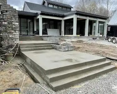 a house with a large concrete patio with steps leading up to a large house