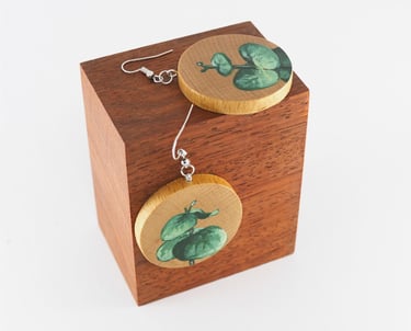 wooden earrings hand painted with leaves motif, displayed on wooden cube