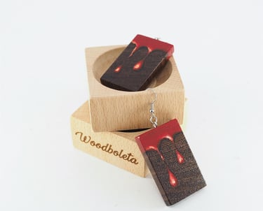 wooden earrings hand painted with paint dripping motif, displayed on wooden cube display