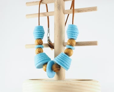 necklace made from blue felt circles and wooden beads, on wooden stand