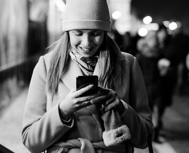 Eine Frau in Mantel und Hut schaut auf ihr Telefon