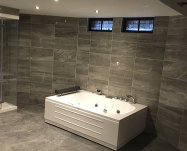 Badkamer met grijs tegels en massagebad 