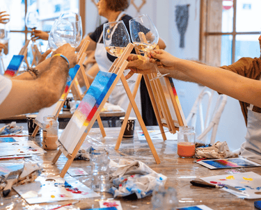 Cilvēki gleznošanas meistarklasē ar vīnu