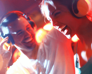 Smaidīgs vīrietis un sieviete ballītē ar austiņām