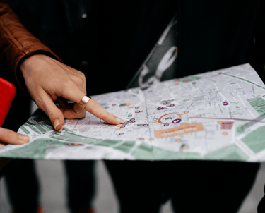 Cilvēki skatās fiziskā kartē un rāda uz vietu