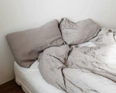 a single bed that is unmade with two pillows