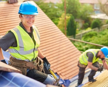 happy roofing worker smiling for the camera while the other installs