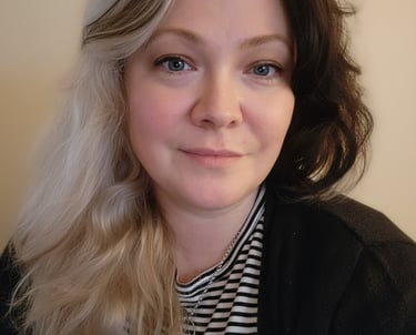 A woman with blue eyes and split-dye blonde and black hair wearing a striped shirt.
