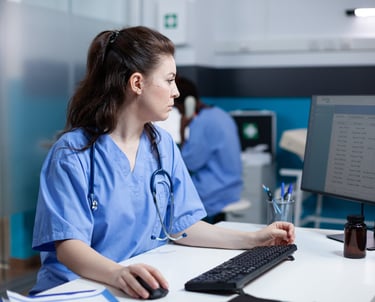 a woman in scrubs and scrubs sitting at a computer