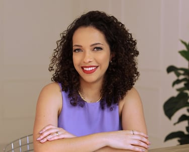 Mulher cacheada sorridente com braços cruzados, oferecendo serviços de coloração pessoal