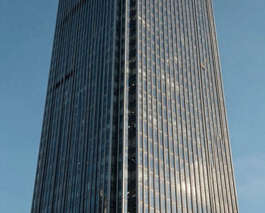 A detailed, architectural photograph of a modern glass skyscraper in a North American financial district, captured with sharp lines and a clear blue sky to represent real estate growth.