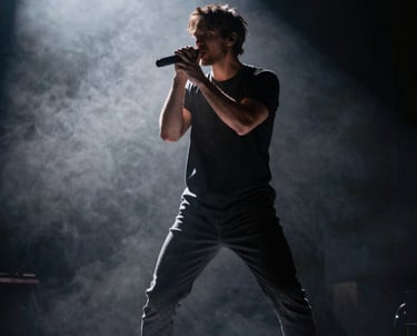 Artist performing on a dark stage with heavy backlighting and fog, cinematic photography, dramatic and powerful mood.