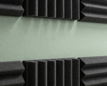 Studio detail of soundproofing panels in dark charcoal with a soft sage green light strip, modern and professional.