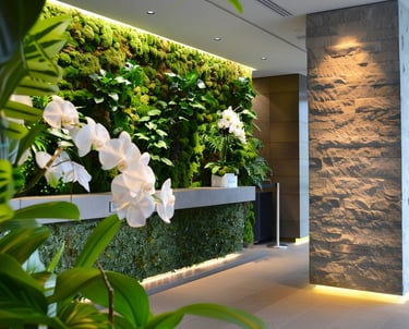 Modern hotel lobby featuring a lush vertical moss wall and white orchid blossoms beside a stone pillar.