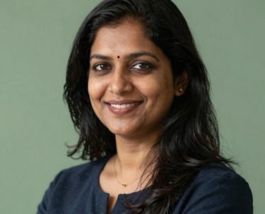 Professional headshot of an Indian female placement expert, friendly and professional, with a sage green background.