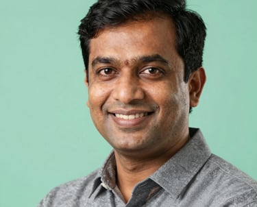 Professional headshot of a male Indian educator in his 30s, smiling, mint green background, professional studio lighting.