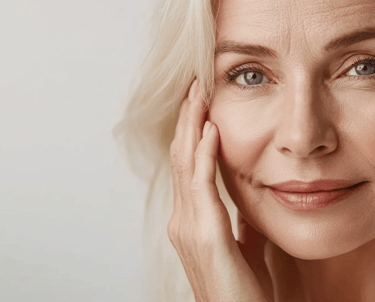 Close-up of a smiling mature woman with blonde hair showcasing healthy aging skin and natural skincare.