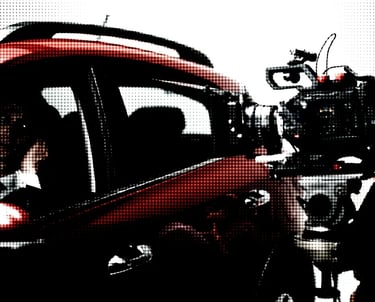Film camera facing actor in car.