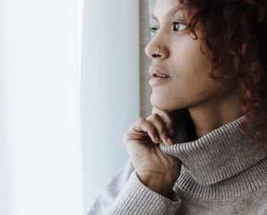Woman in turtleneck looking thoughtfully out of a window