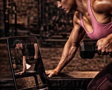 Fit woman lifting dumbbells while following an online fitness class on a smartphone at the gym.