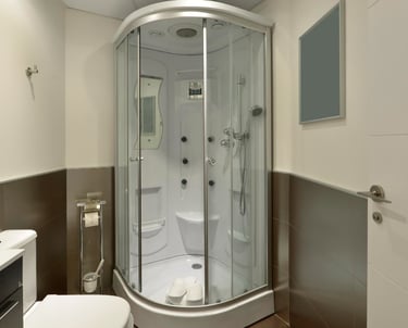 Semi-circular glass shower enclosure with hydromassage panel, sink and toilet