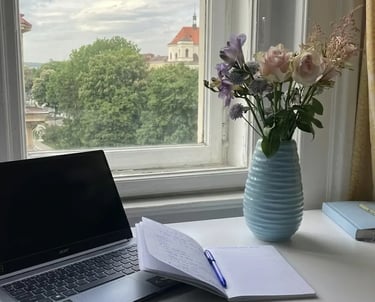 Espaço de trabalho sereno com luz natural suave, notebook aberto, caderno e vaso com flores 