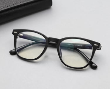 A close-up of stylish budget-friendly eyeglasses resting on a wooden table with soft natural light.