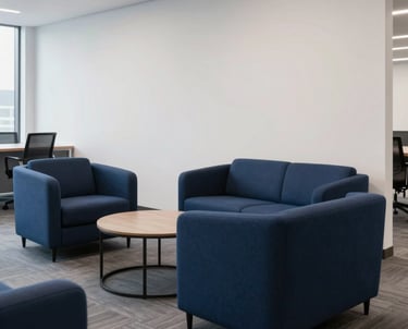 A professional shot of a modern office lounge area with stylish navy blue furniture and clean white walls. The lighting is soft and inviting. Representative of a high-quality North American work environment.