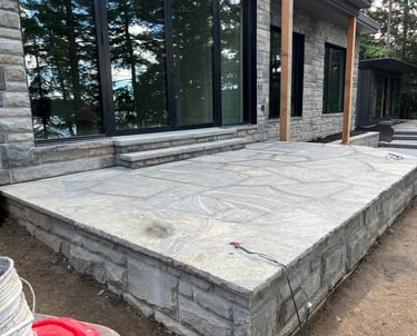 Custom natural flagstone patio and stone retaining wall outside a modern lakeside home.