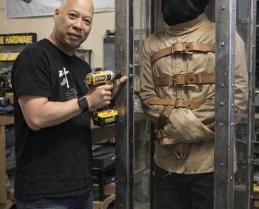 Ray Lum A custom fabrication designer uses a power drill on a metal and glass escape room prop