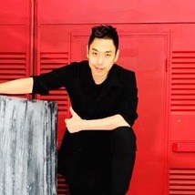 Eun Gyeol Leeposing in front of bright red lockers with modern art.