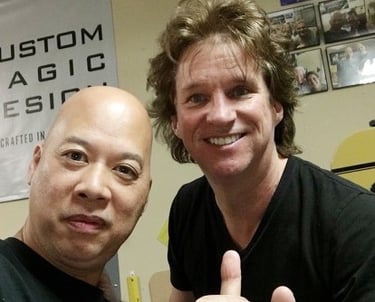 Ray and Greg Gleason smiling for a selfie at a custom magic design studio.