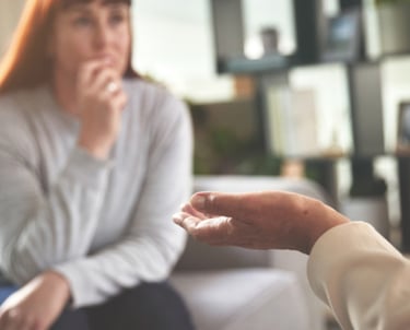 A woman appears deeply thoughtful during a life coaching session.