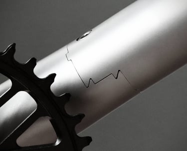 Z-coupler titanium bicycle frame with a black chainring and interlocking joint design.