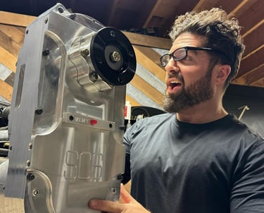 don abenante holding a high-performance SCS gear drive transfer case in a workshop.