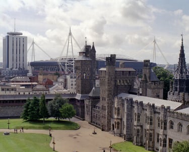 Cardiff Castle grounds featuring historic stone architecture with the modern Principality Stadium in the background.