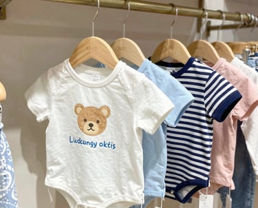 Brightly colored baby sweatshirt hanging on a small wooden hanger