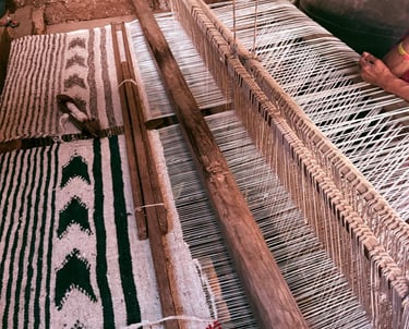 Textil artesanal con patrones geométricos siendo tejido en un telar tradicional de madera 