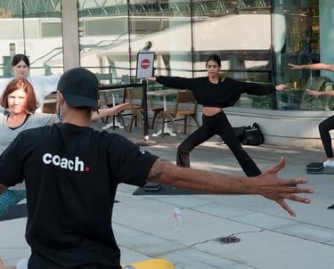 A diverse fitness group practices yoga poses during an outdoor class with a coach.