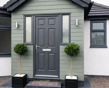 A bespoke modern porch in Portslade, built with a dark grey door, sage green horizontal cladding, and outdoor lighting.
