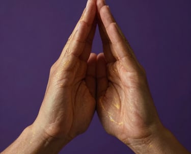 Close-up photography of hands positioned in a sacred energy healing gesture, soft ethereal light shimmering in golden hues against a deep royal purple background, global/western.