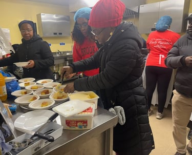 Volunteers in a soup kitchen serving hot meals and desserts to community members in need.