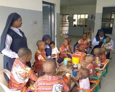 Our Sisters feeding some young children during snack time at the St. Joseph Orphanage.