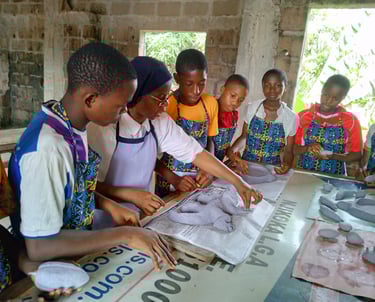 Students and teacher crafting paper sculptures during an art workshop in an African classroom.