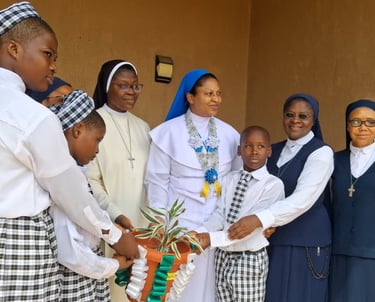 Catholic nuns and school children holding a potted plant together at a religious ceremony.