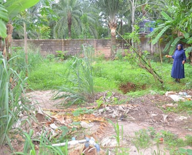 A Catholic nun standing in a lush tropical garden with banana trees and palm plants.