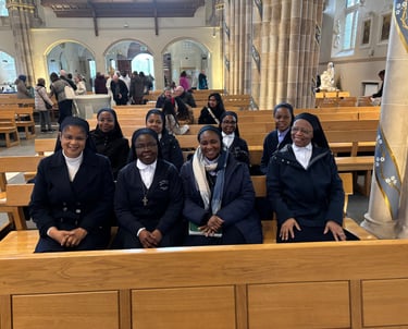 A group of Catholic nuns in habits sitting together in wooden pews inside a cathedral church.