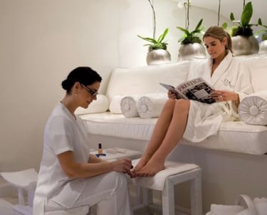 A woman in a white robe enjoys a professional pedicure treatment at a luxury spa.